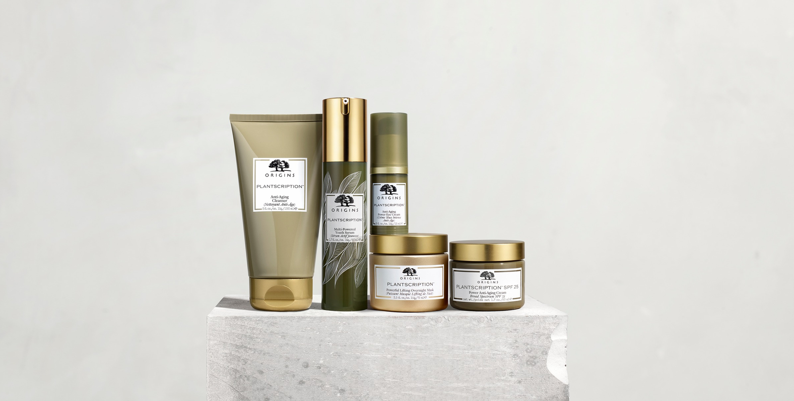 A selection of products available from Origins placed on a gray block.